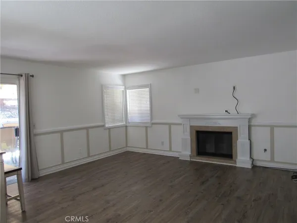an empty room with wooden floor a fireplace and windows