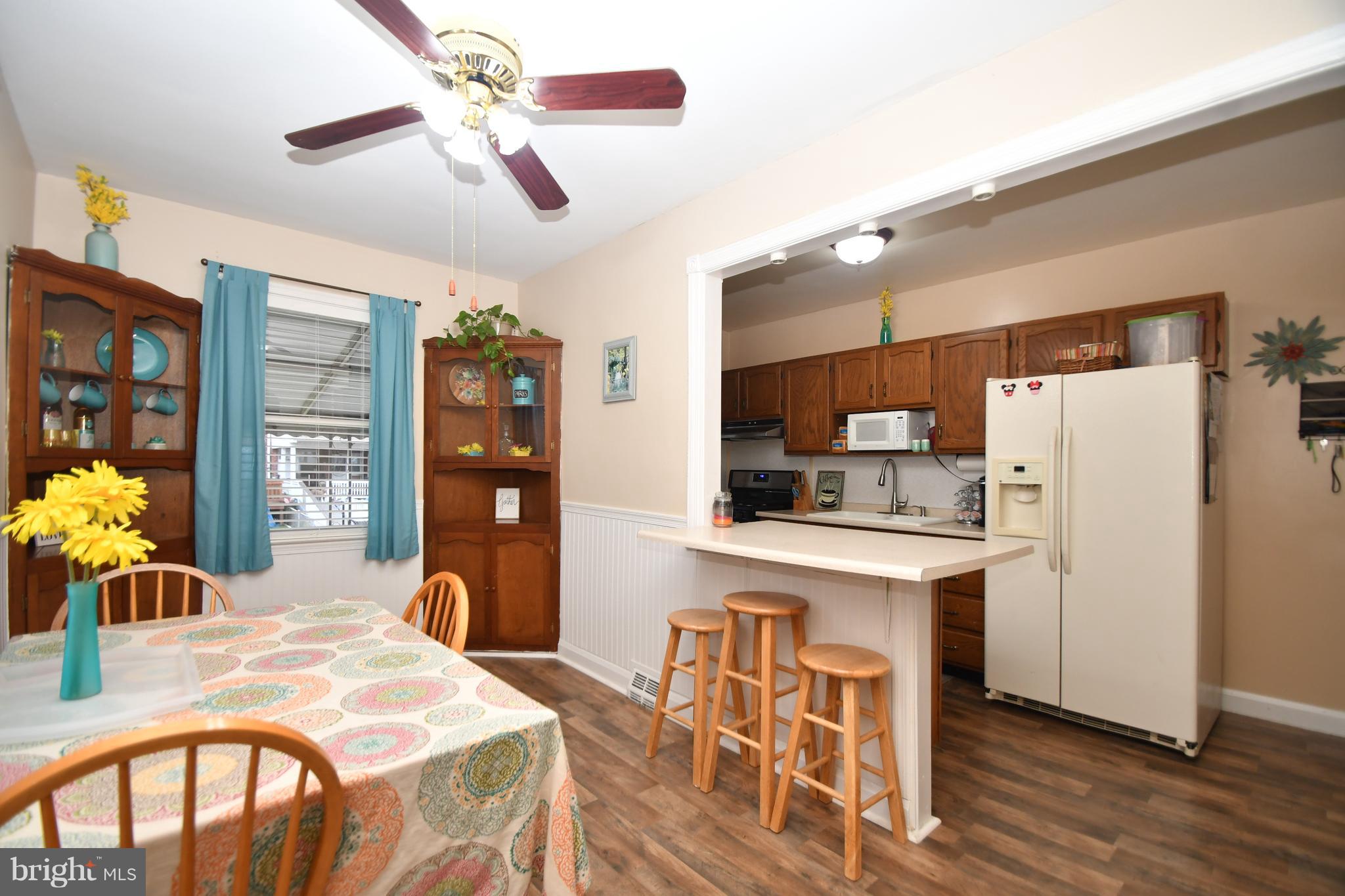 58 Berkshire Road Baltimore, MD 21221 - Photo 12 of 41 a kitchen with stainless steel appliances kitchen island granite countertop a refrigerator a stove top oven and a dining table with wooden floor
