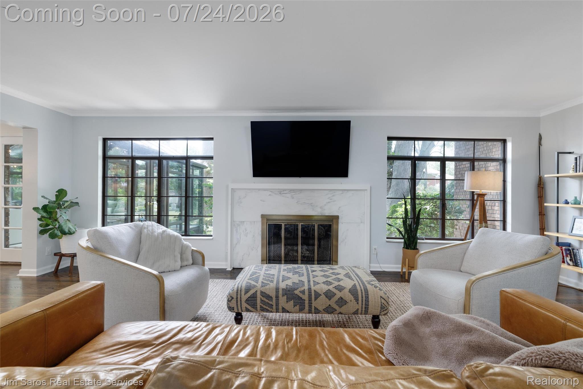 757 Middlesex Road Grosse Pointe, MI 48230 - Photo 18 of 45 Living space featuring a prominent fireplace with a marble surround and hearth, dark wood-finish flooring, two large multi-pane windows with dark frames, and white painted walls with crown molding