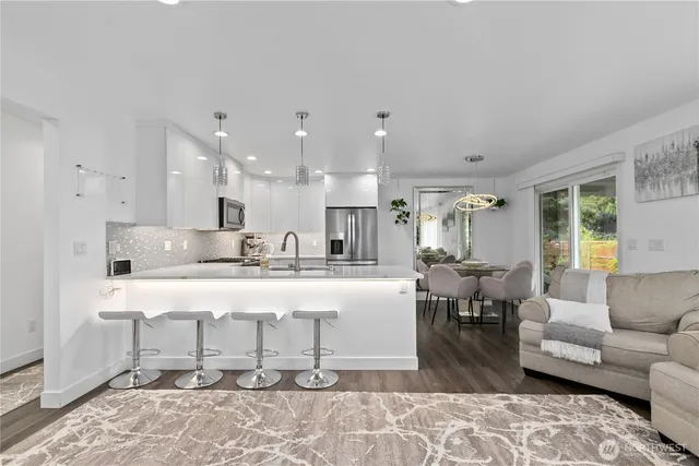 a kitchen with a dining table chairs cabinets wooden floor and appliances