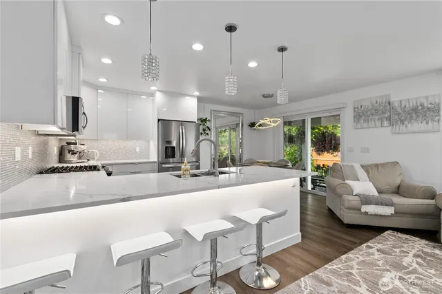 a kitchen with a sink dishwasher a dining table chairs with wooden floor