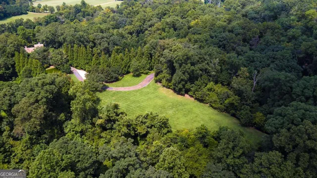 an aerial view of residential house with outdoor space and trees all around