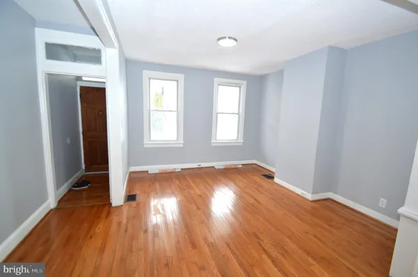 an empty room with wooden floor and windows