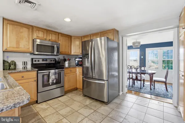 a kitchen with granite countertop a refrigerator and a stove top oven