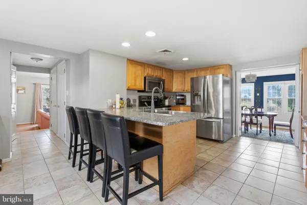 a kitchen with stainless steel appliances granite countertop a stove a sink a dining table and chairs
