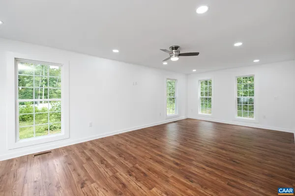 a view of empty room with wooden floor and fan