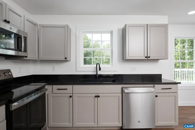 a kitchen with granite countertop white cabinets white appliances and a sink