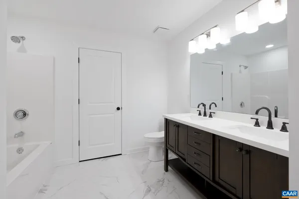 a bathroom with a double vanity sink a toilet and shower