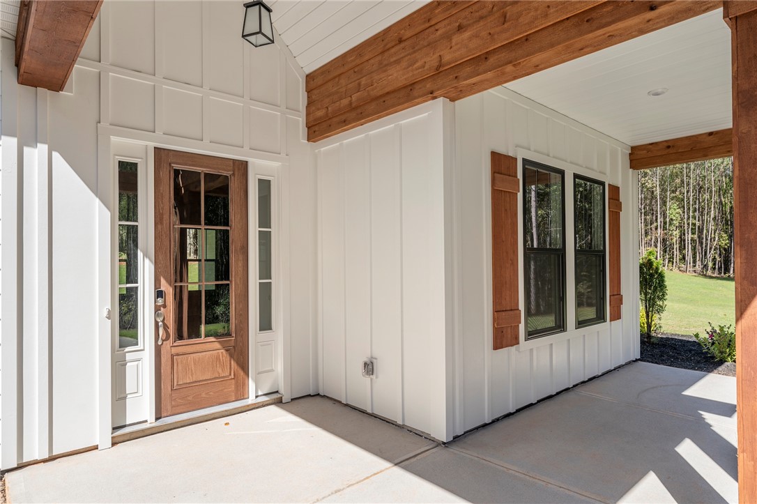 1031 Hill Road Anderson, SC 29621 - Photo 4 of 35 A welcoming front entry features a glass-paneled wooden door, board and batten siding, and rustic wooden shutters.