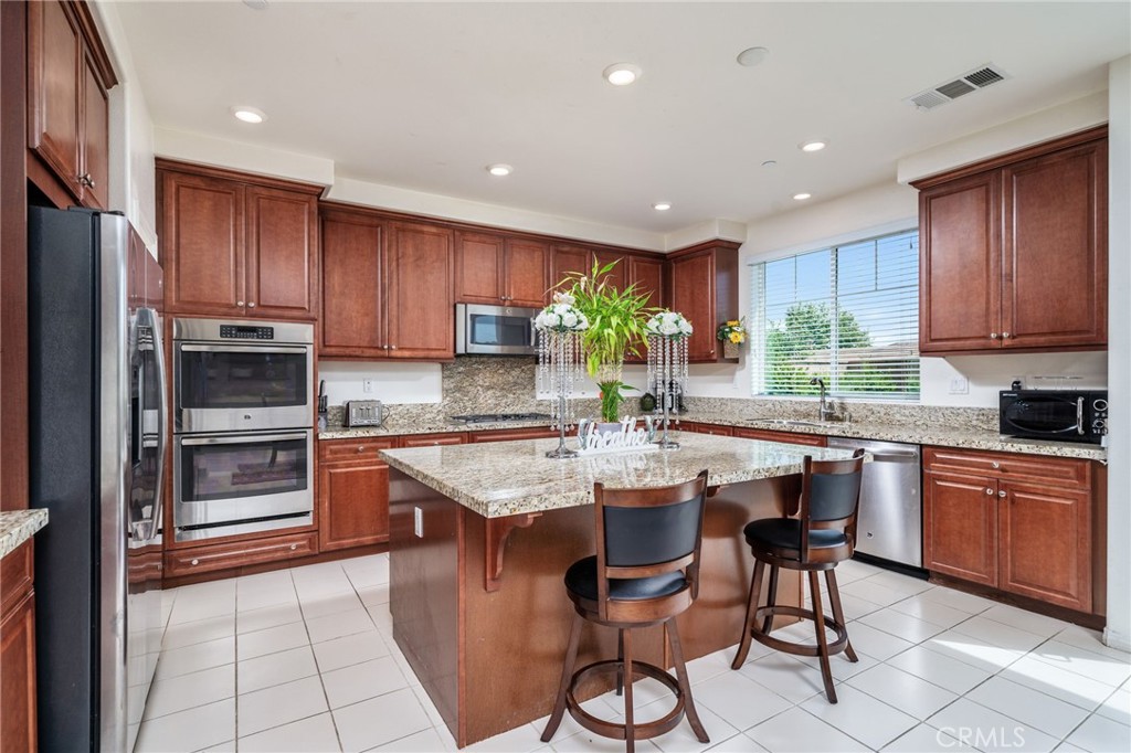 13243 Stanton Drive Rancho Cucamonga, CA 91739 - Photo 16 of 53 a kitchen with stainless steel appliances granite countertop wooden cabinets a stove top oven a sink and dishwasher