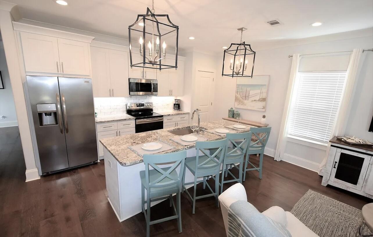 92 Heron's Crossing Santa Rosa Beach, FL 32459 - Photo 3 of 28 a kitchen with stainless steel appliances granite countertop a stove a refrigerator a kitchen island a dining table and chairs with wooden floor