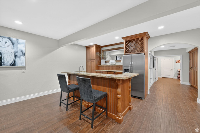 14738 Tangle Hill Road Herriman, UT 84096 - Photo 41 of 66 Built-in wet bar featuring a light wood-finish cabinetry, a stone-finish countertop, and an integrated stainless steel refrigerator