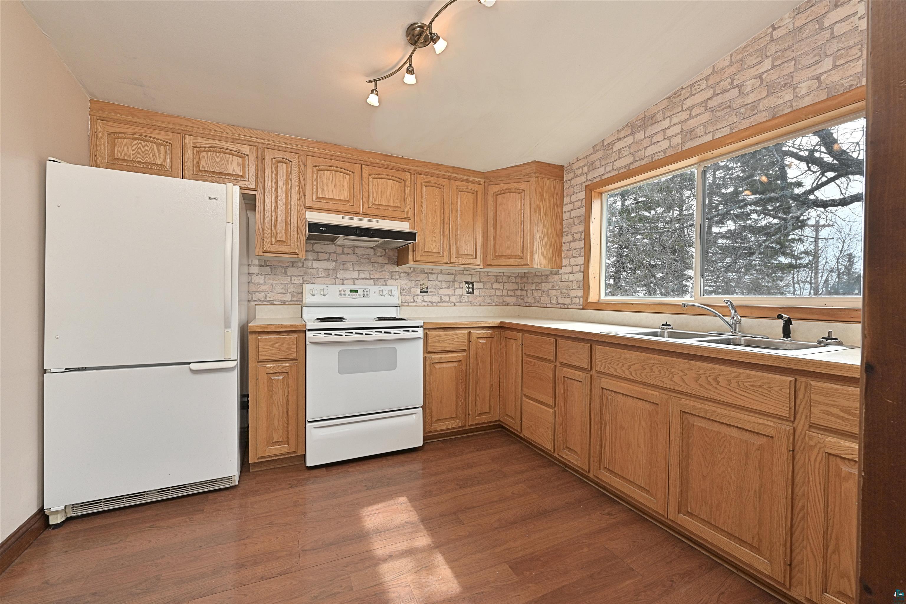 18 Banks Boulevard Silver Bay, MN 55614 - Photo 5 of 26 Kitchen with white appliances, light countertops, dark wood-style flooring, and backsplash