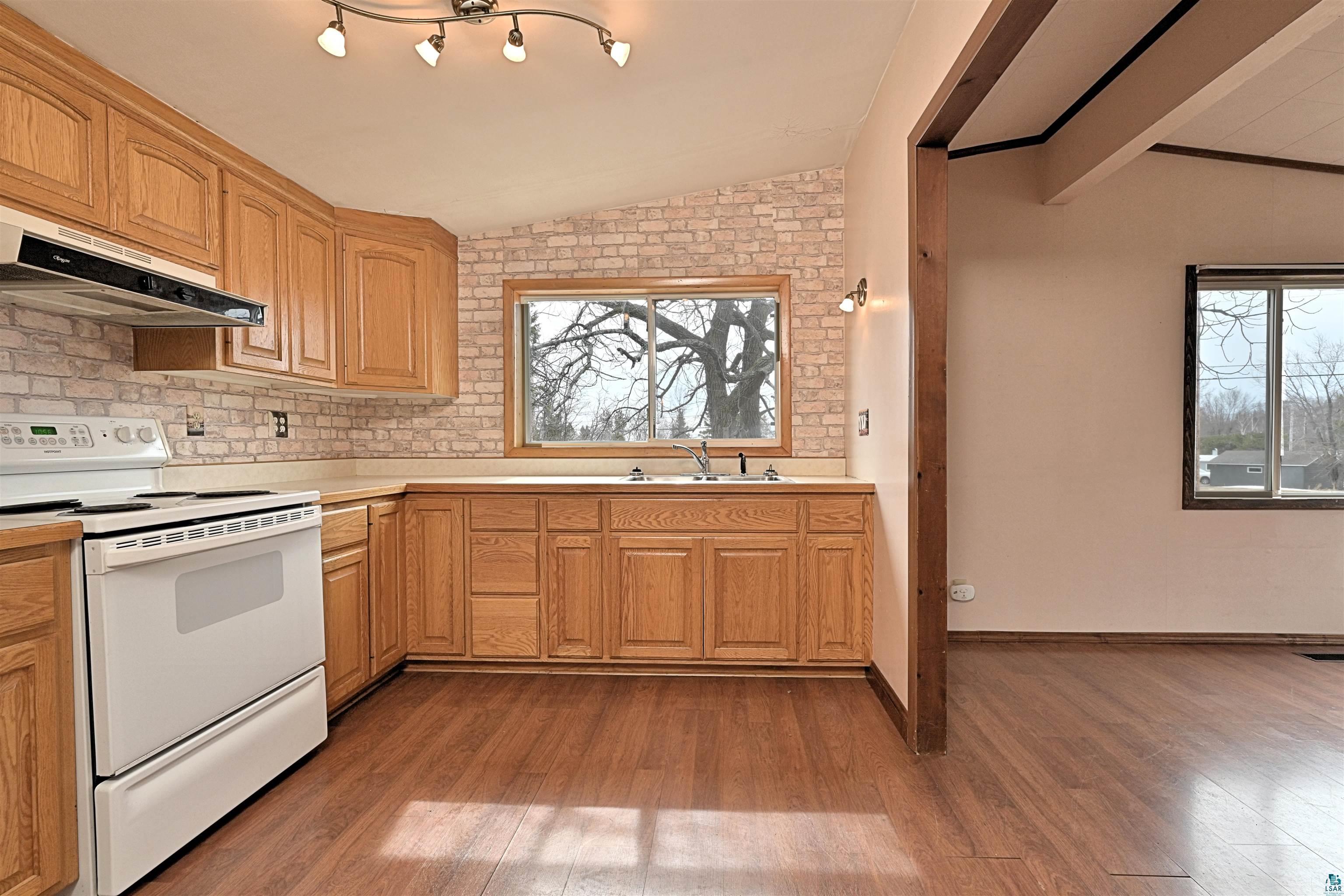 18 Banks Boulevard Silver Bay, MN 55614 - Photo 6 of 26 Kitchen featuring electric stove, light countertops, light wood-style floors, vaulted ceiling, and backsplash