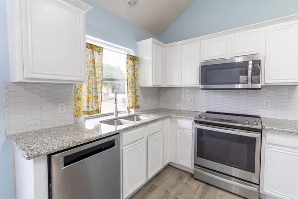 a kitchen with granite countertop a sink stove top oven and microwave