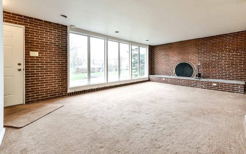 Exotic log burning fireplace on exposed brick with smooth cement raised hearth.