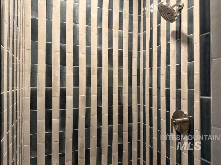 755 West Wrangler Street Meridian, ID 83646 - Photo 10 of 35 Shower interior featuring a vertical tile pattern in contrasting light and dark tones, brushed nickel showerhead, and a coordinating single-handle control