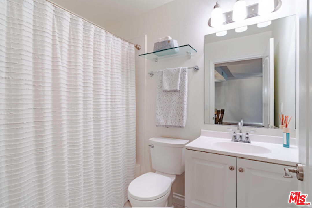956 South Wilton Place, Unit 305 Los Angeles, CA 90019 - Photo 12 of 18 a bathroom with a sink a toilet and shower curtain