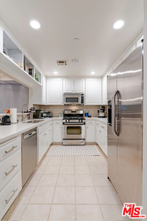 956 South Wilton Place, Unit 305 Los Angeles, CA 90019 - Photo 15 of 18 a kitchen with granite countertop a refrigerator and white cabinets