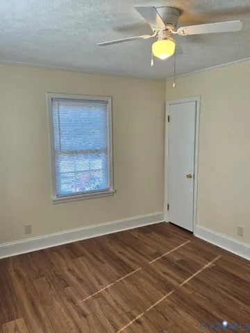 en empty room with wooden floor and fan