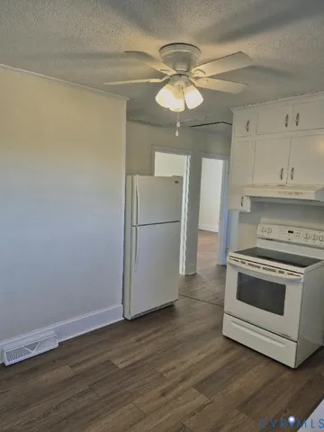a view of a kitchen with a stove a microwave and wooden floor