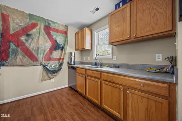 a kitchen with stainless steel appliances granite countertop a sink and cabinets with wooden floor