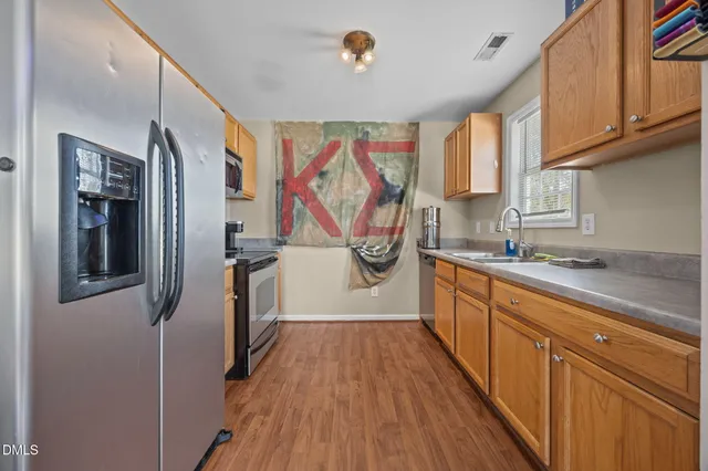 a view of a kitchen with stainless steel appliances granite countertop a refrigerator a sink and wooden floors