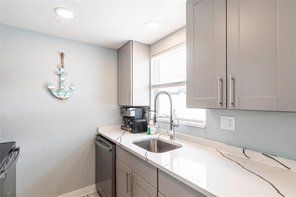 6020 Midnight Pass Road, Unit 49 Sarasota, FL 34242 - Photo 8 of 38 a kitchen with a sink cabinets and window