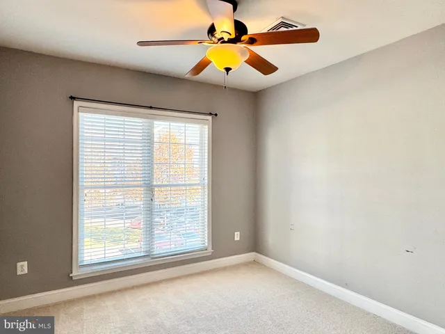 an empty room with a window and a chandelier fan