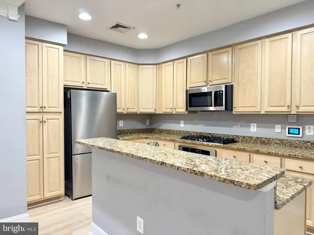 a kitchen with granite countertop a refrigerator a sink a stove a microwave and cabinets