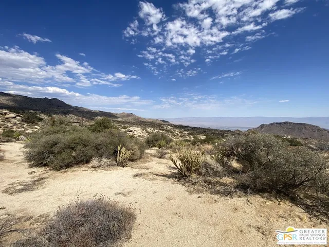 a view of a dry yard with mountains in the background