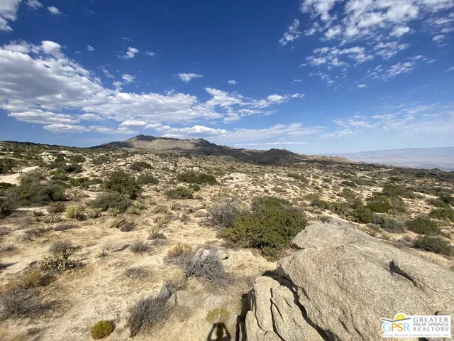 a view of a dry yard with mountains in the background