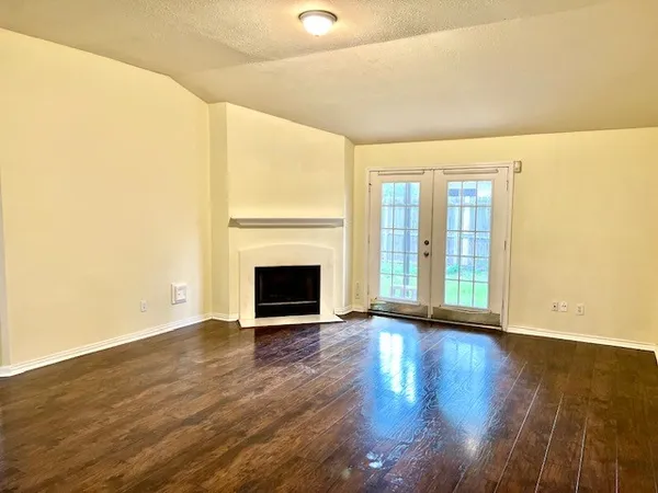 a view of an empty room with wooden floor and a fireplace