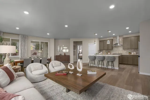 a living room with furniture a wooden floor and kitchen view