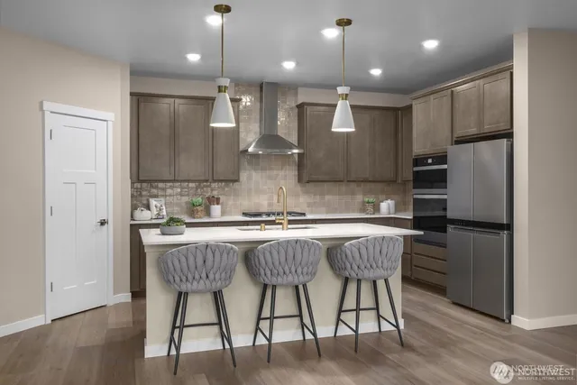 a kitchen with stainless steel appliances granite countertop a center island wooden floor and a refrigerator