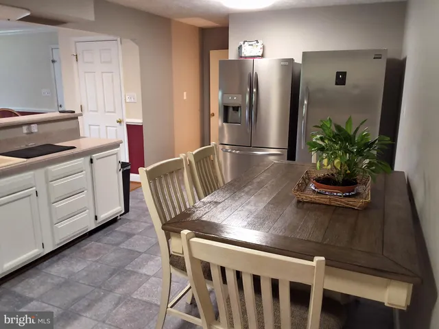 a kitchen with stainless steel appliances granite countertop a table chairs and a refrigerator