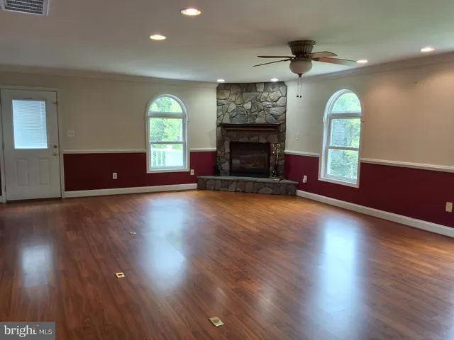 an empty room with windows wooden floor and fireplace