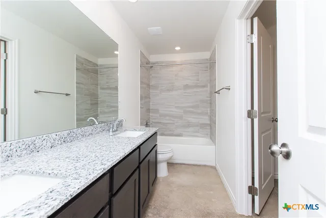 a bathroom with a granite countertop sink a toilet and shower