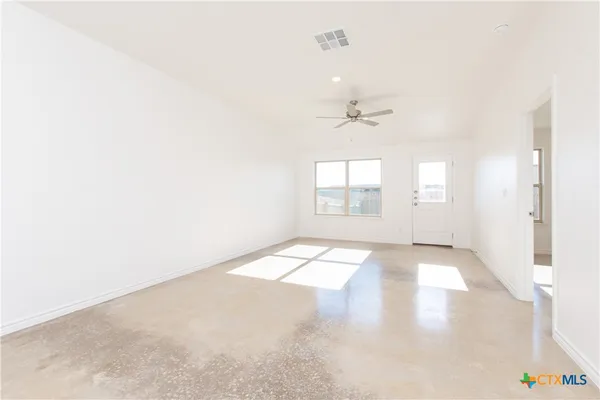 an empty room with windows and ceiling fan
