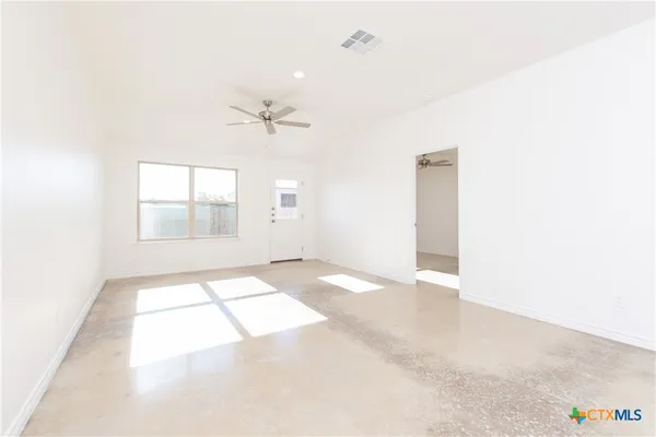 an empty room with windows and ceiling fan