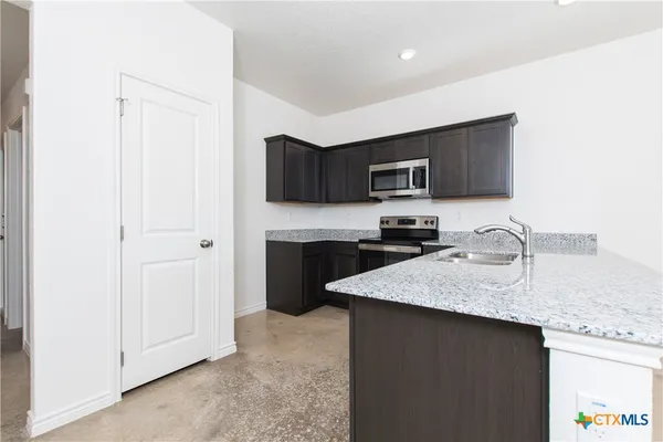 a kitchen with granite countertop a refrigerator stove top oven a sink and dishwasher