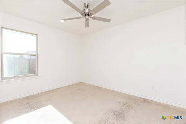 an empty room with a window and a fan