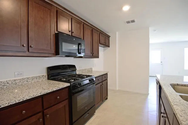 a kitchen with stainless steel appliances granite countertop a stove a sink and a microwave