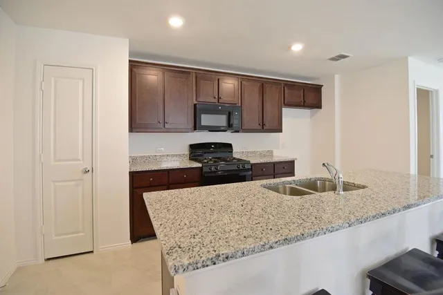 a kitchen with granite countertop a sink and a refrigerator