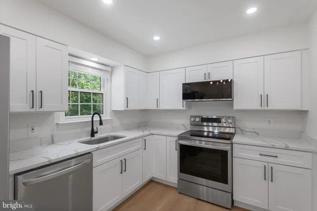 a kitchen with granite countertop a sink a stove a microwave and wooden cabinets