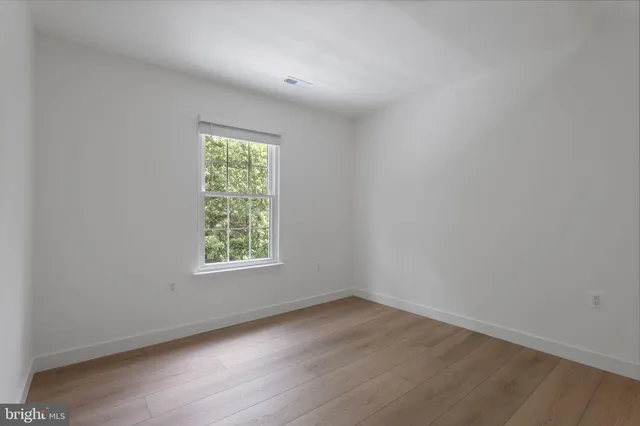 an empty room with wooden floor and a window