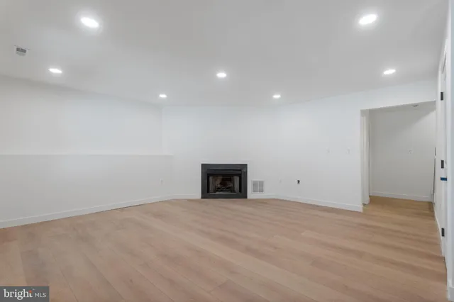 a view of empty room with wooden floor and fireplace