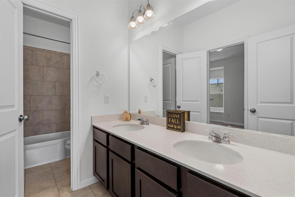236 Prato Place Georgetown, TX 78628 - Photo 30 of 40 A well-appointed bathroom features a double vanity and sleek countertops, with a tiled tub/shower combination.
