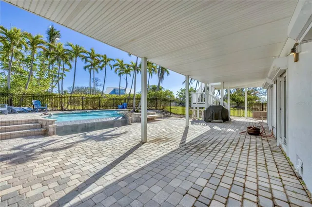 a view of a swimming pool with a lawn chairs and palm trees
