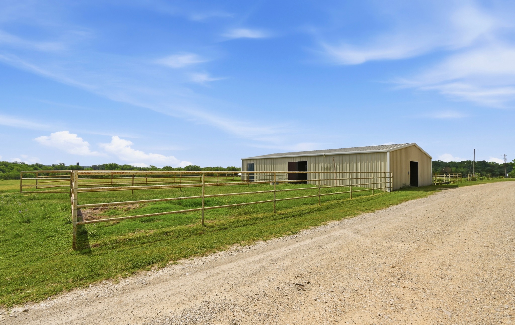 1175 Southern Way Luling, TX 78648 - Photo 12 of 40 Acres of open pasture land border a functional barn, perfect for agricultural pursuits.